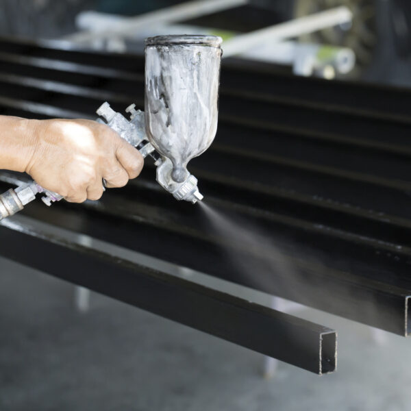 Male holding spray gun and painted steel